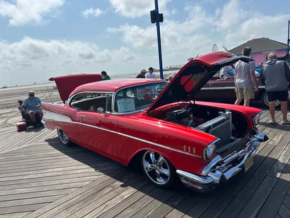 A red classic car with its hood open at a car show on the Wildwood boardwalk