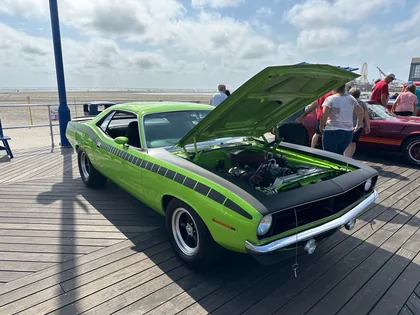 A lime-green classic coupe with its hood open beside the Wildwood beach
